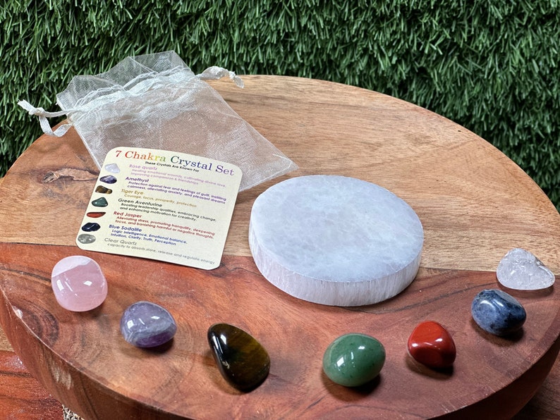Beautiful collection of healing crystals and gemstones arranged with fresh roses, candles, and spiritual oils on an elegant wooden surface, showcasing natural stones for manifestation, protection, and positive energy.