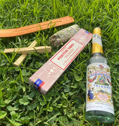 Sacred incense sticks, sage bundles, and spiritual colognes artfully arranged with fresh roses, crystals, and candles on an elegant wooden table, creating a mystical display for purification and energy cleansing rituals.